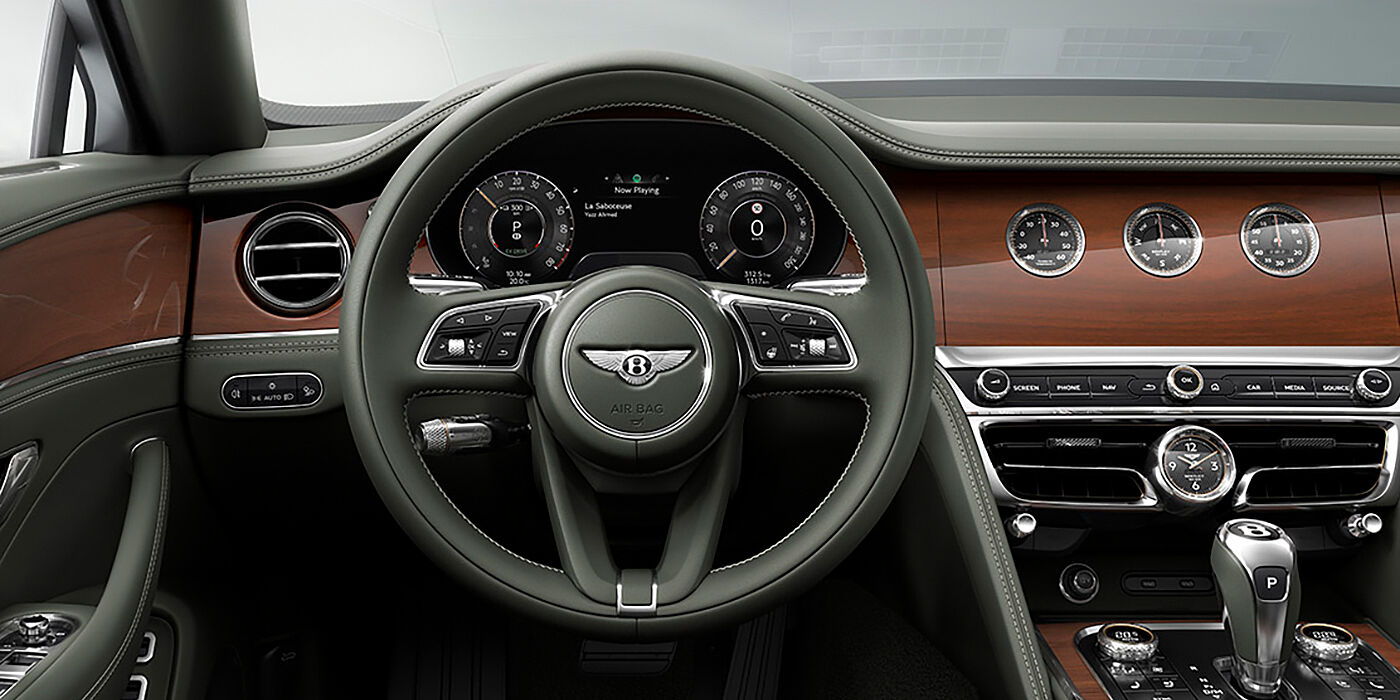 Bentley Guatemala New Bentley Flying Spur sedan front cabin in Cumbrian Green hide and Crown Cut walnut veneer showing steering wheel and Rotating Display with three clocks on face