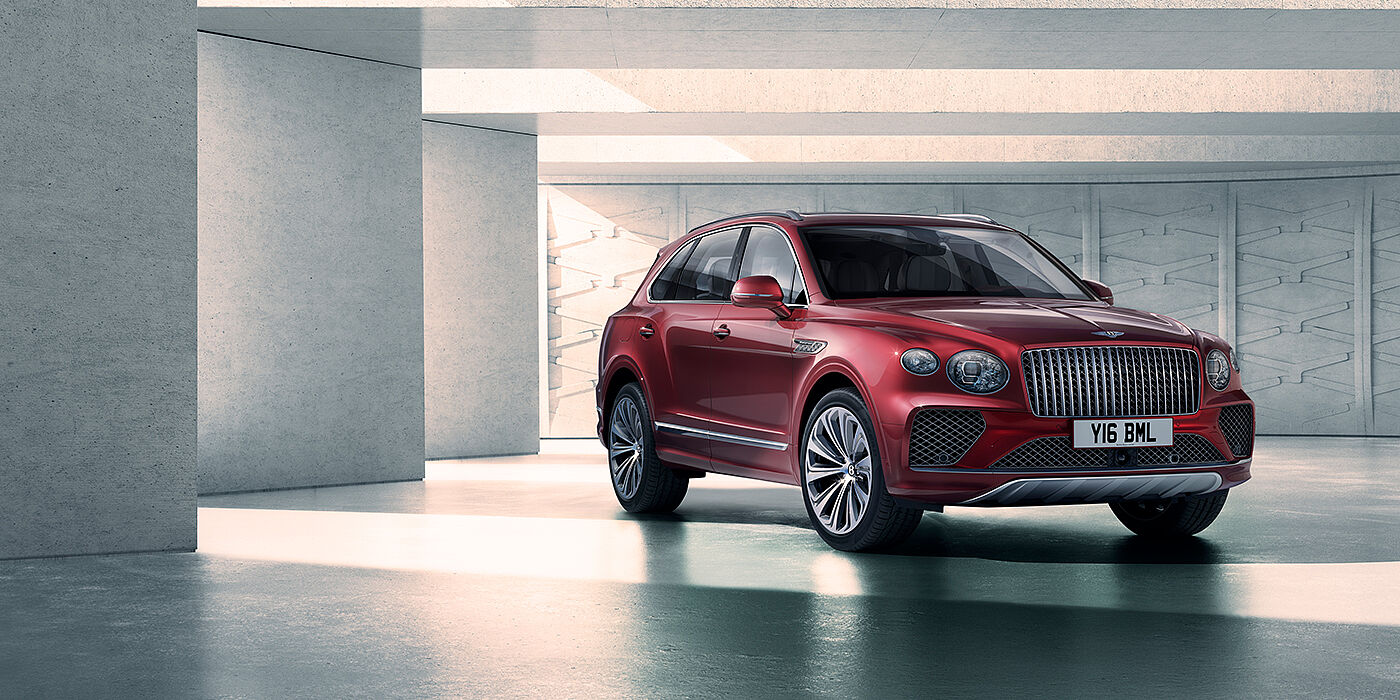 Bentley Guatemala Bentley Bentayga Atelier Edition SUV in Rubino Red paint front three quarter against textured concrete wall