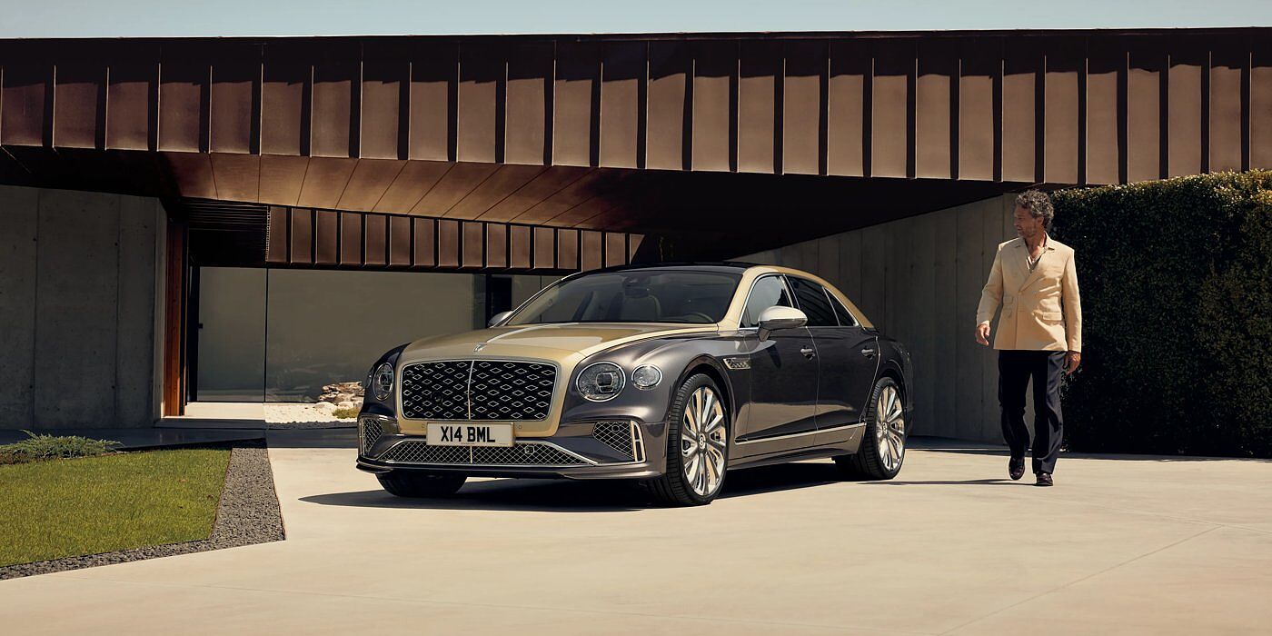 Bentley Guatemala Bentley New Flying Spur Mulliner V8 hybrid sedan front three quarters in Rose Gold over Magnetic paint, parked near modern home