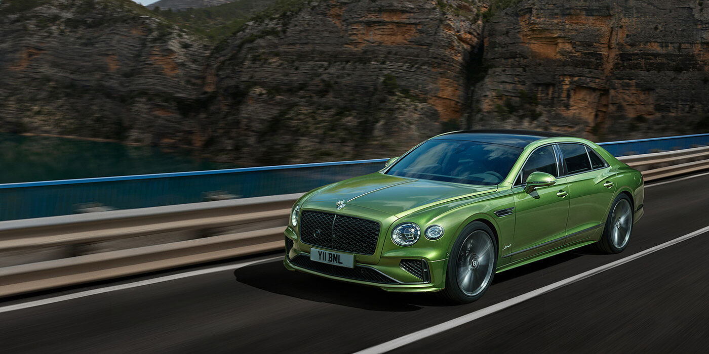 Bentley Guatemala Bentley New Flying Spur Speed v8 hybrid sedan driving dynamically on a mountain road in Tourmaline Green paint