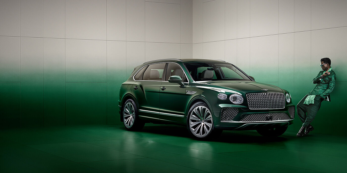Bentley Guatemala Wisdom K leans against wall next to Bentley Bentayga Extended Wheelbase Atelier Edition SUV in Light Emerald green paint