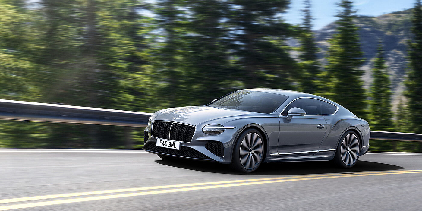 Bentley Guatemala New Bentley Continental GT coupe in Silverlake paint and 22 inch ten-spoke wheels, driving dynamically on a tree-lined road in the sunshine