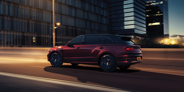Bentley Guatemala Bentley Bentayga Extended Wheelbase Mulliner SUV in Cricket Ball red paint driving dynamically in city at night