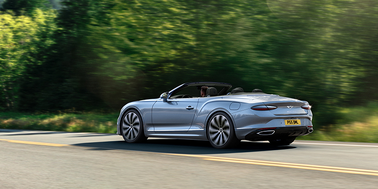 Bentley Guatemala New Bentley Continental GTC convertible side view in Silverlake paint with 22 inch ten spoke wheels driving dynamically on a country road